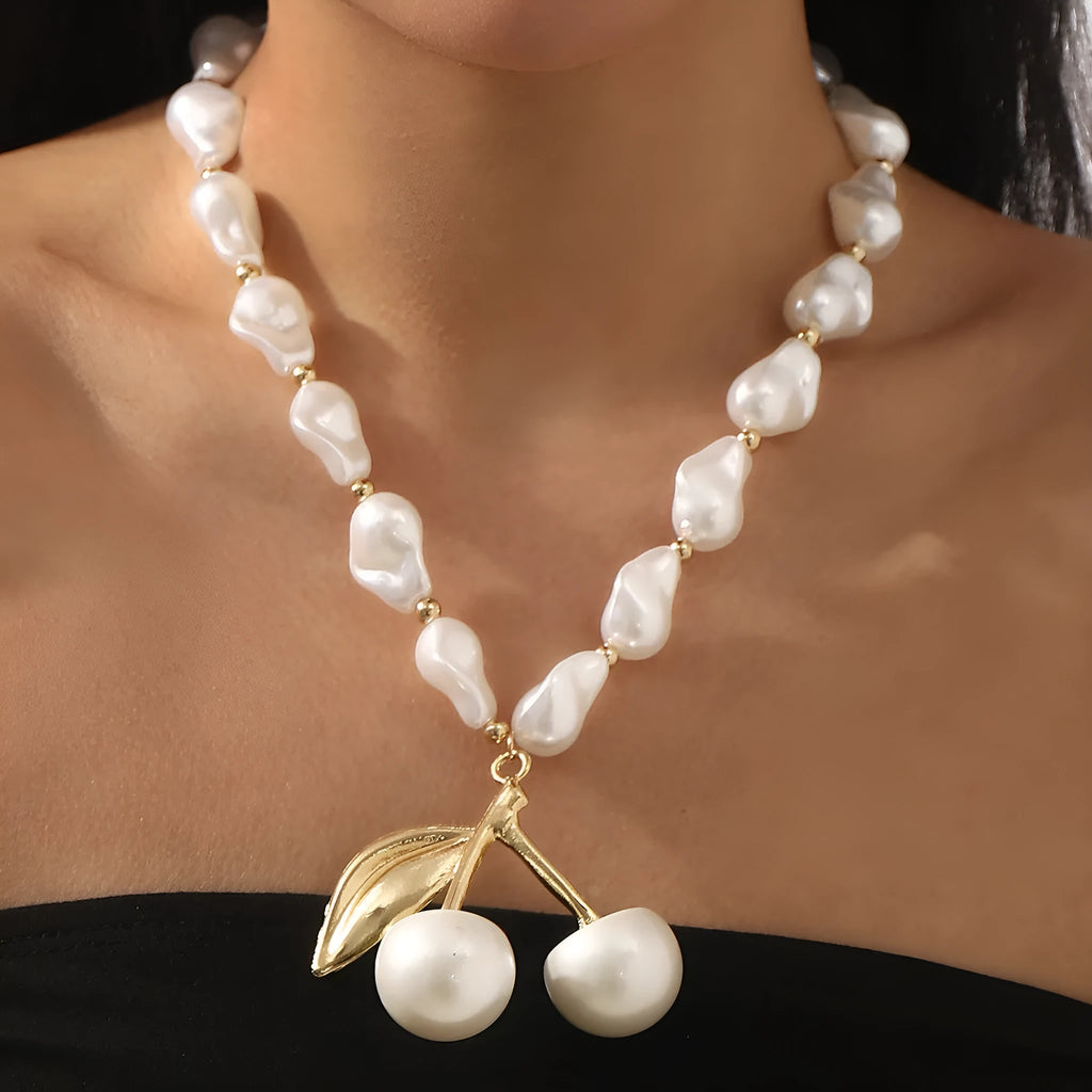 Gold tone irregular necklace with cherry fruit pendant and adjustable string of round pearls on a model