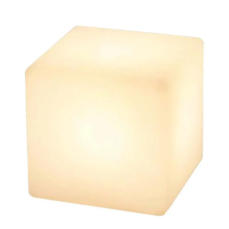 A modern square white LED cube light stool in a garden setting, showing its size options.