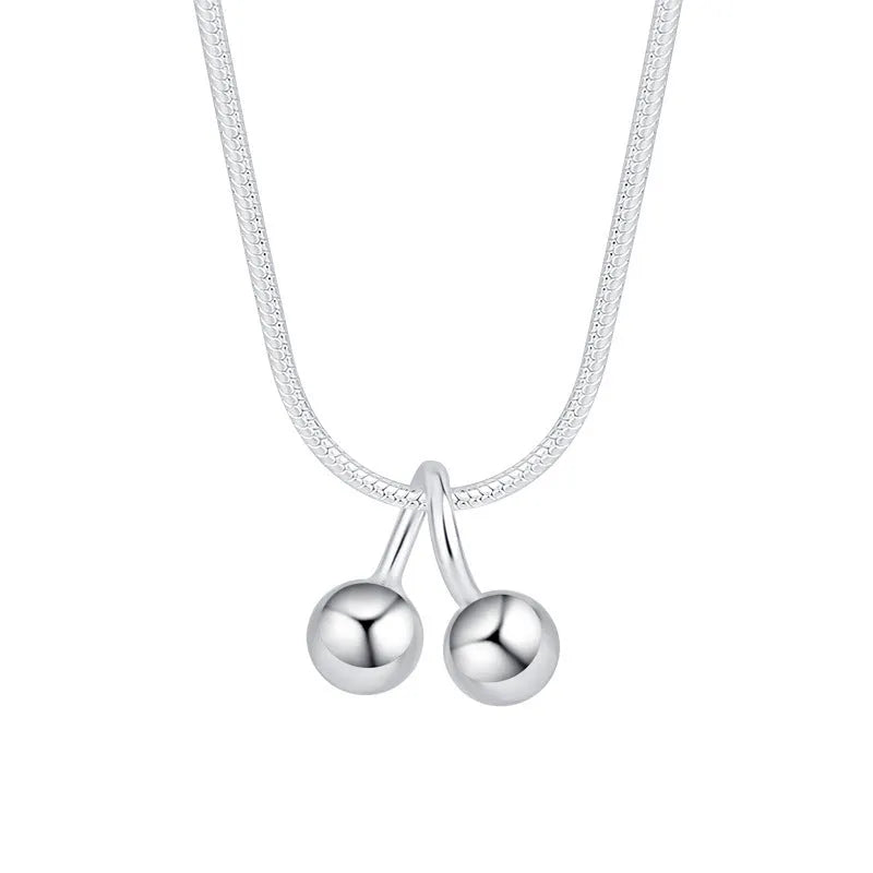 Close-up of a silver cherry pendant necklace on a textured snake bone chain, adjustable from 21cm to 50cm.
