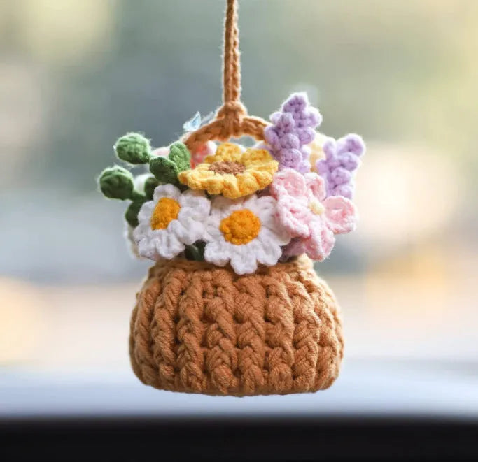 Green and white crocheted wool car plant decoration with a white hanging rope.