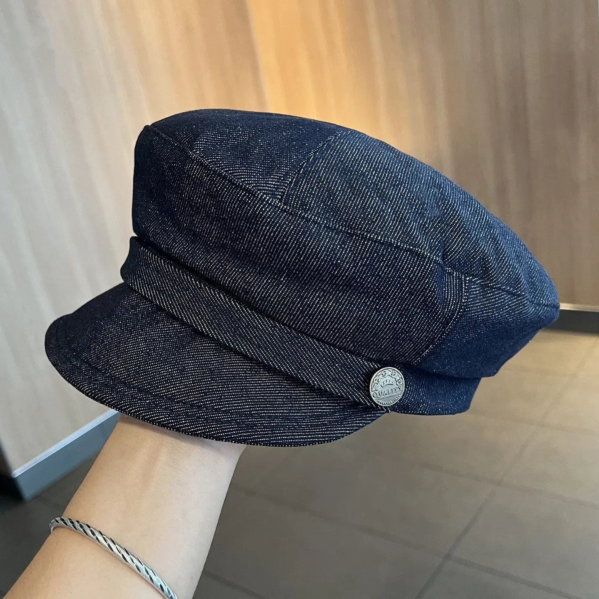 Dark blue denim octagonal newsboy flat cap with an adjustable strap, shown with a contrasting brown brim.