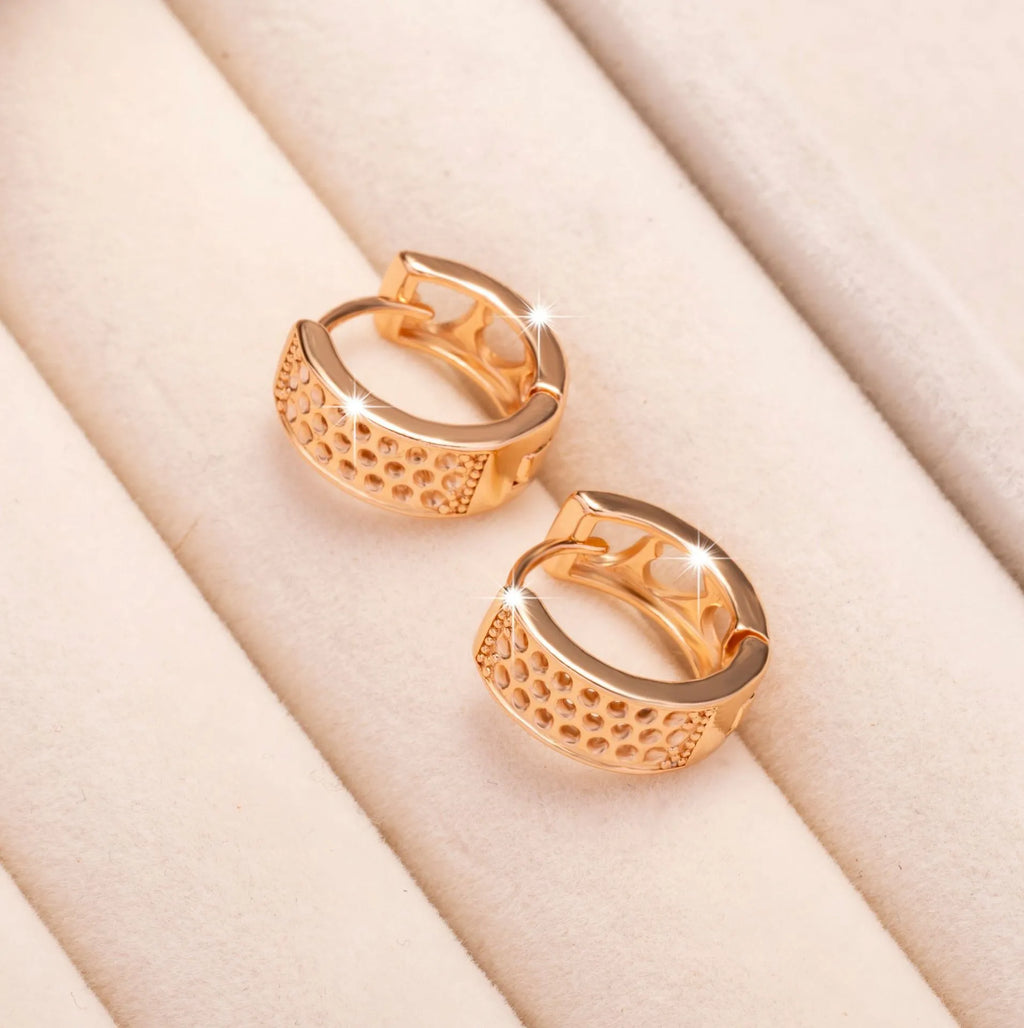 A pair of circular rose gold tone earrings featuring a hollowed-out heart shape design on a white background.