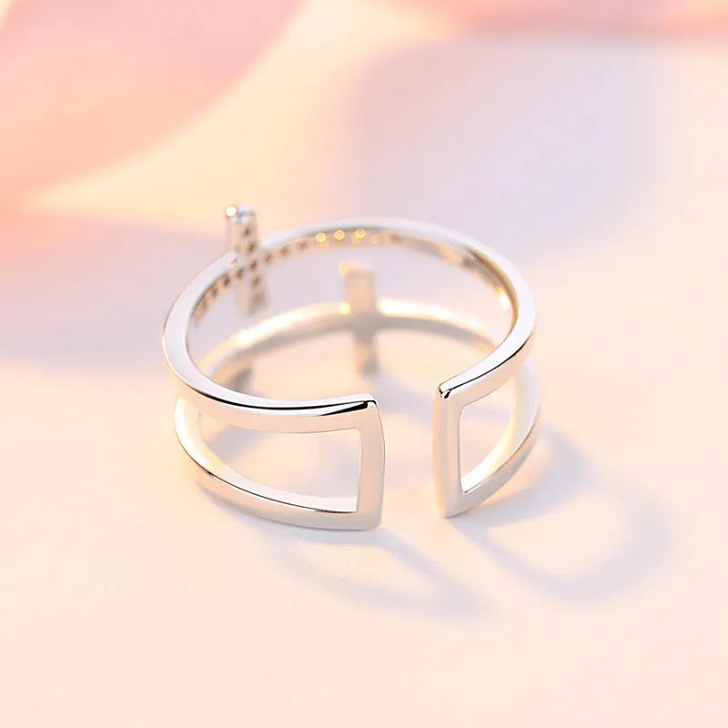 Close-up of a women's adjustable copper ring featuring a miniature double cross design with a zircon stone set in sterling silver.