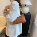 A structured black pleated women's shoulder bag with a chain strap and a soft handle, showing its square shape.
