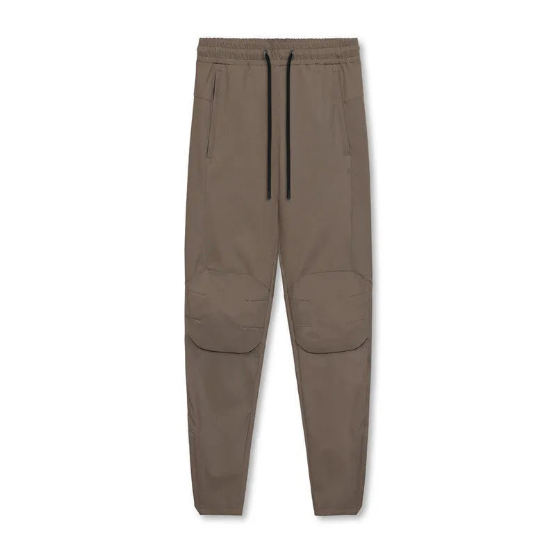 Man wearing dark grey loose-fit fitness trousers with tied ankle cuffs, made from quick-dry polyester fabric.