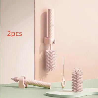 Pink and green electric rotating bottle cleaning brush with silicone bristles on a white background.