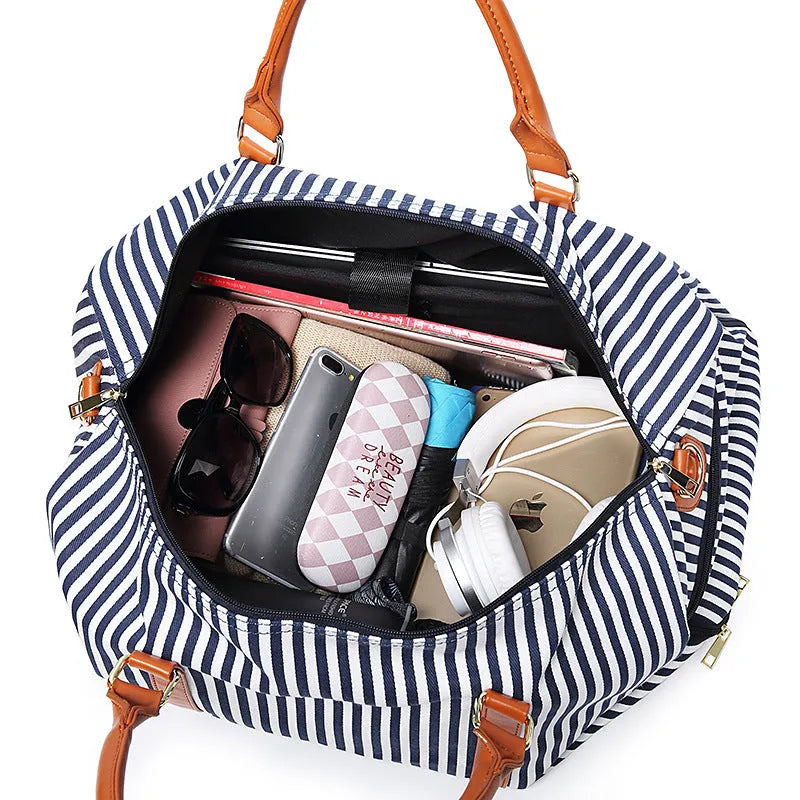 Large striped canvas travel duffel bag with contrast colour and leather detailing, horizontal square shape and zip top.