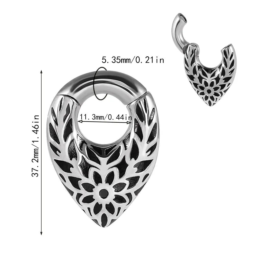 A single stainless steel teardrop-shaped ear extender for stretched lobes, showing a totem pattern on its face.