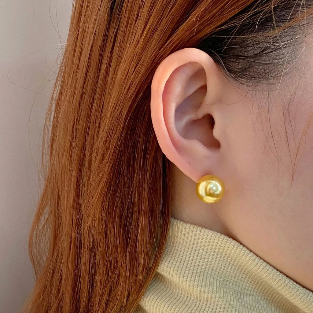 A pair of large geometric pearl stud earrings with a retro design on a silver setting.