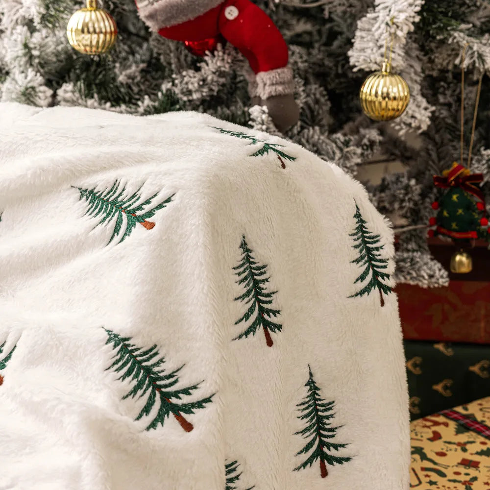 White plush sofa blanket with embroidered Christmas tree design on a sofa