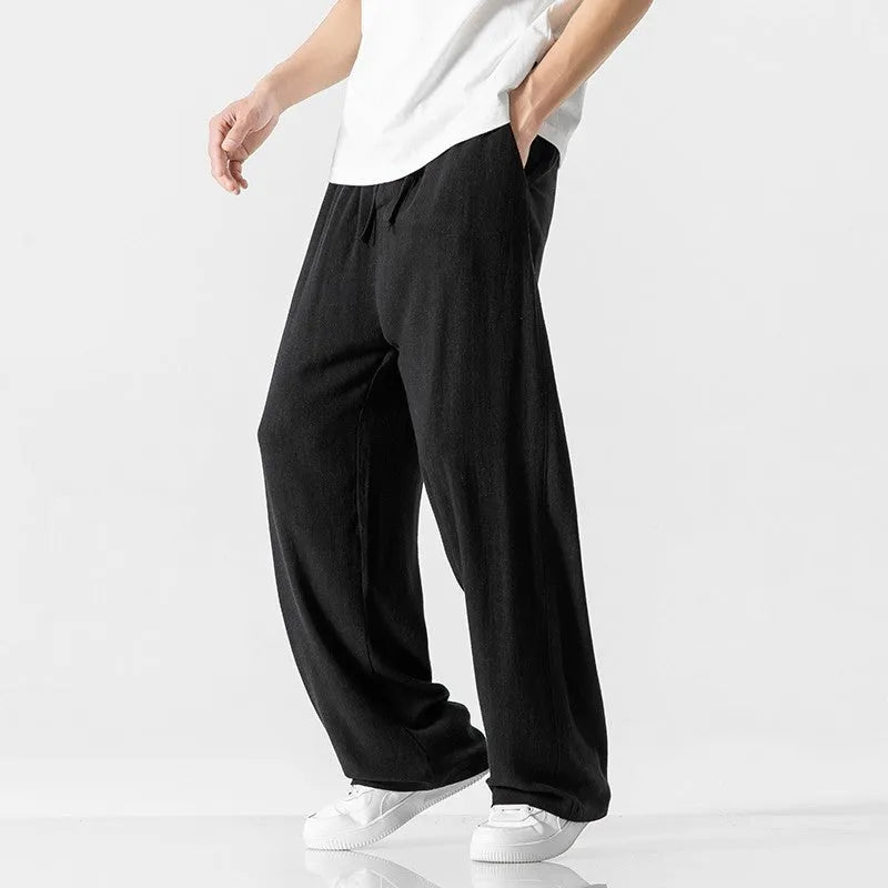 Man wearing beige bamboo fibre cropped trousers with a drawstring waist and straight legs.