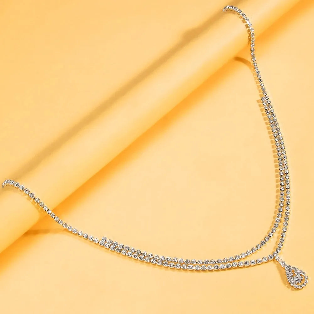 Gold rhinestone water drop pendant on a 115cm adjustable waist chain with lobster buckle.