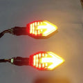 Arrow-shaped LED motorcycle turn signal light unit for 12V vehicles, shown in available colour options.