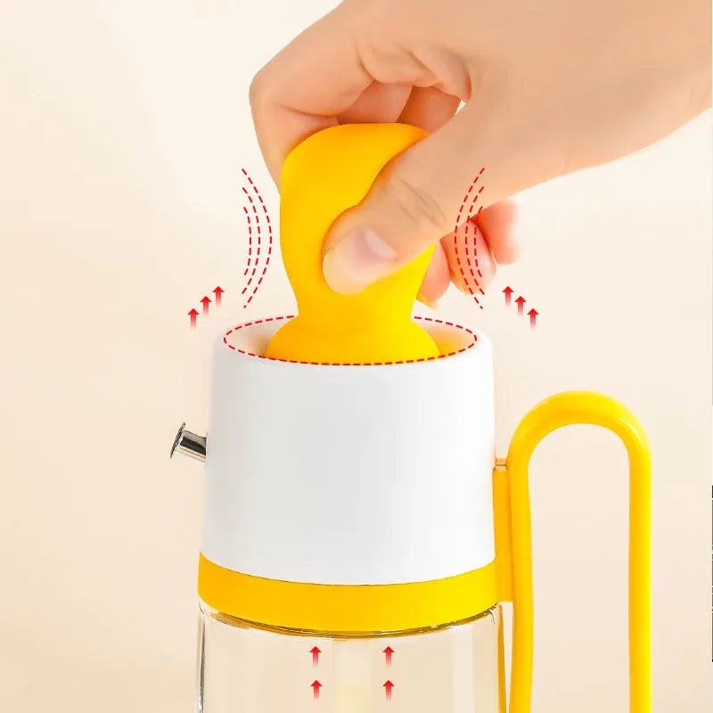 550ml clear glass oil dispenser bottle with stainless steel spray nozzle and a yellow silicone brush head attached.