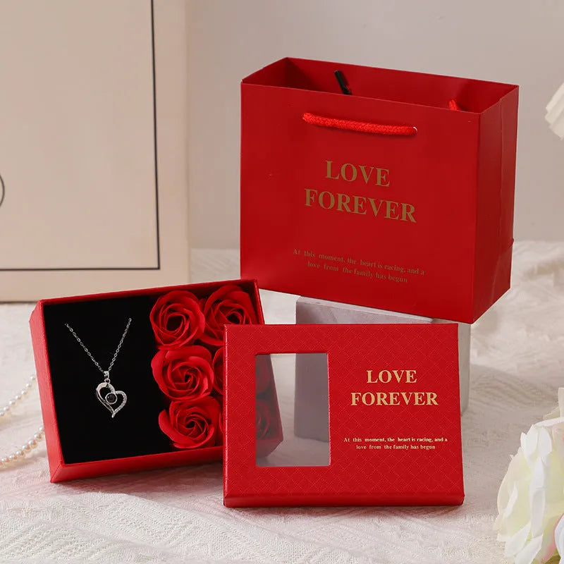 Red Valentine's gift box open to show six pink soap roses with a matching handbag beside it