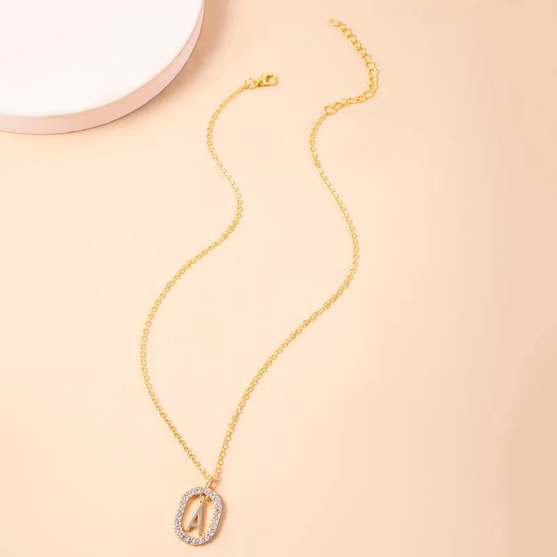 Gold crystal letter necklace with rhinestone initial on oval pendant and O-chain