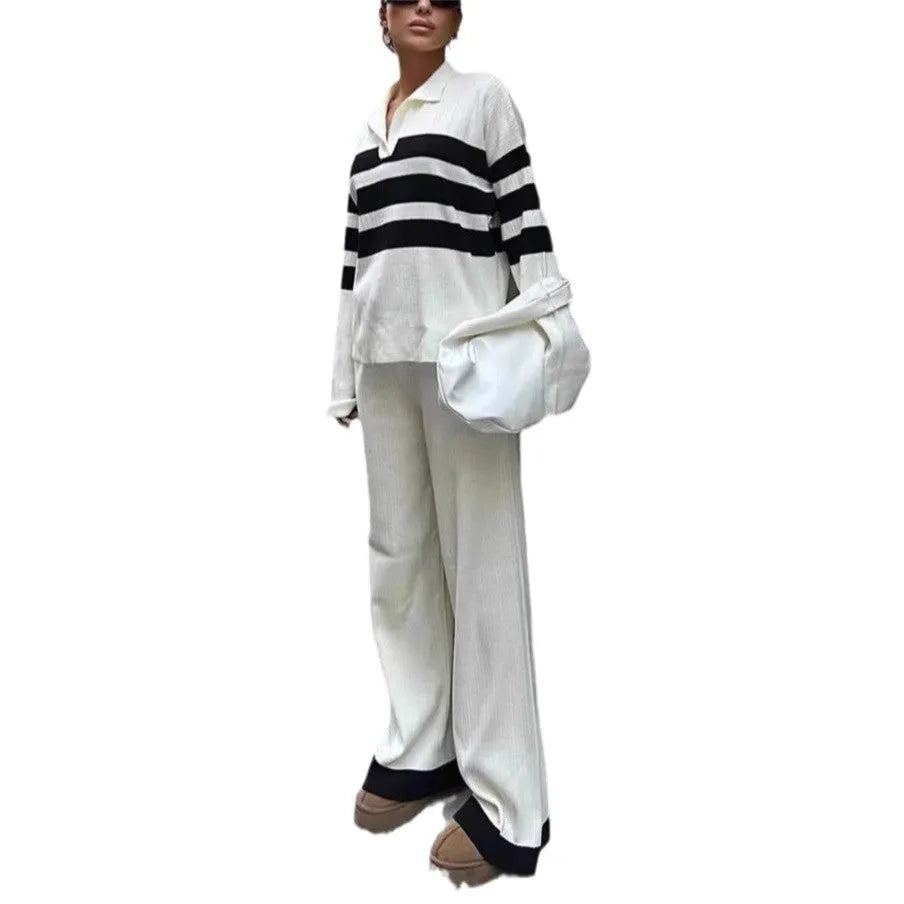 Women's black and white striped knitted two-piece set with polo collar top and straight-leg trousers laid flat.