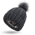 Women's knit beanie hat with faux fur pom pom in wine red, showing satin lining with paisley pattern.