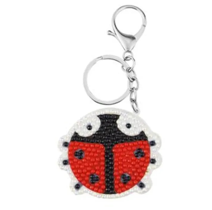 Diamond painting keychain kit showing four animal designs: ladybird, Santa Claus, unicorn, and owl with resin diamonds and metal keyring