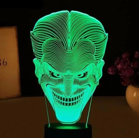 Compact USB-powered 3D LED desk lamp with a touch switch and remote control on a desk.