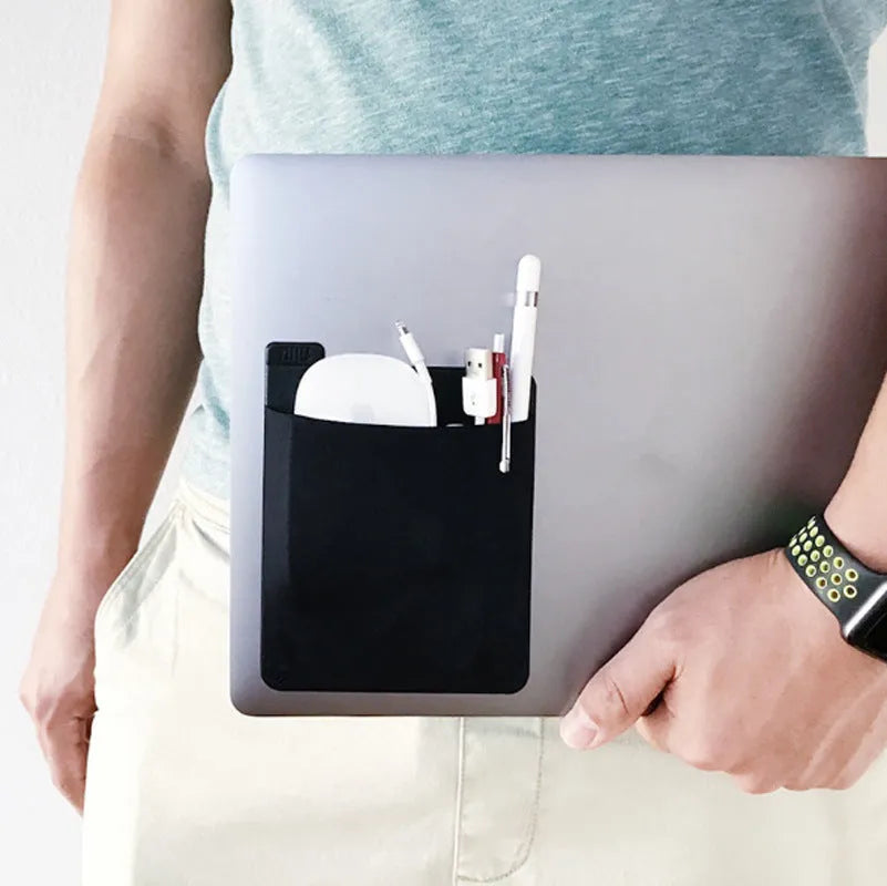 Black adhesive laptop back storage bag attached to a laptop, 15x12 cm, with pen loop and small items inside