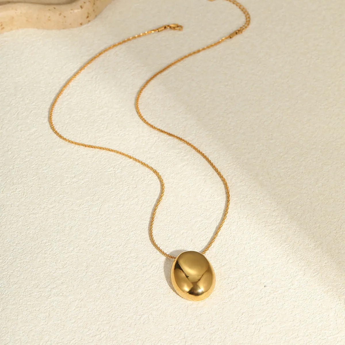Gold geometric pendant necklace on a stainless steel chain with adjustable length.
