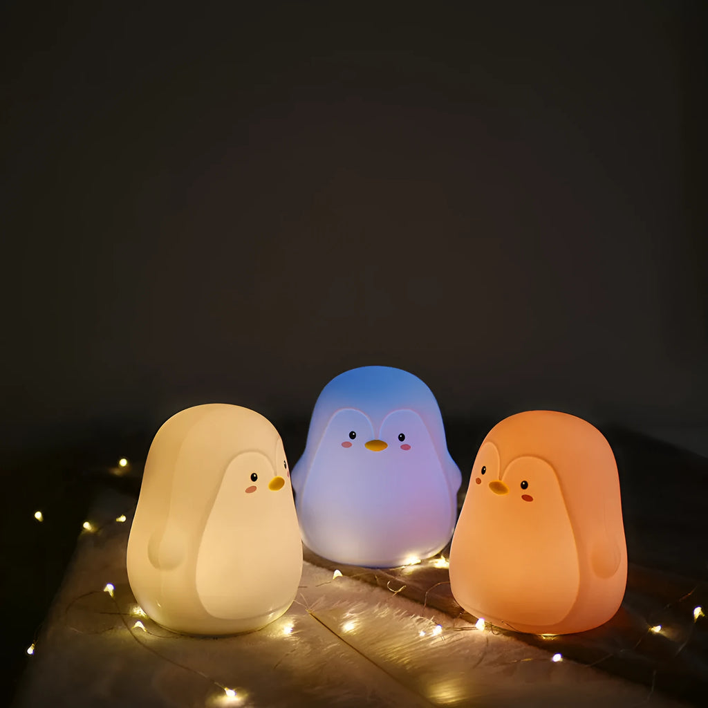 White USB rechargeable penguin-shaped night light with soft glow, shown next to its charging cable.