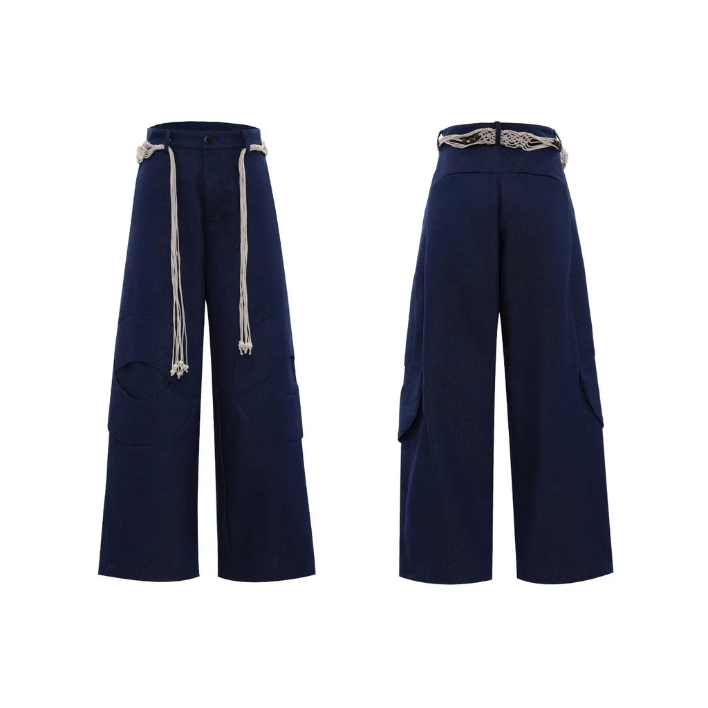 Men's dark blue straight-leg jeans showing loose fit, belt stitching with tassel, and zip pocket decorations.