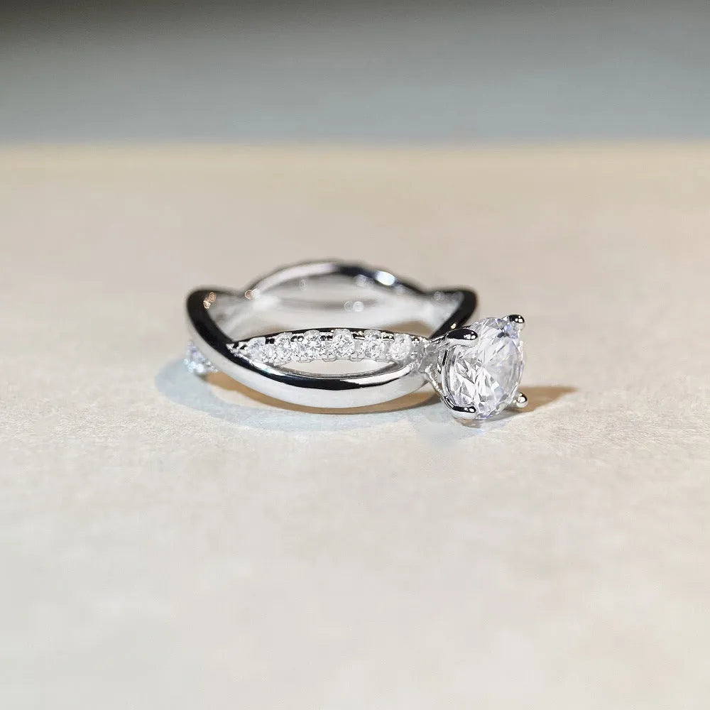 A silver ring with a 1 karat moissanite stone in a four-claw setting on a twisted geometric band.