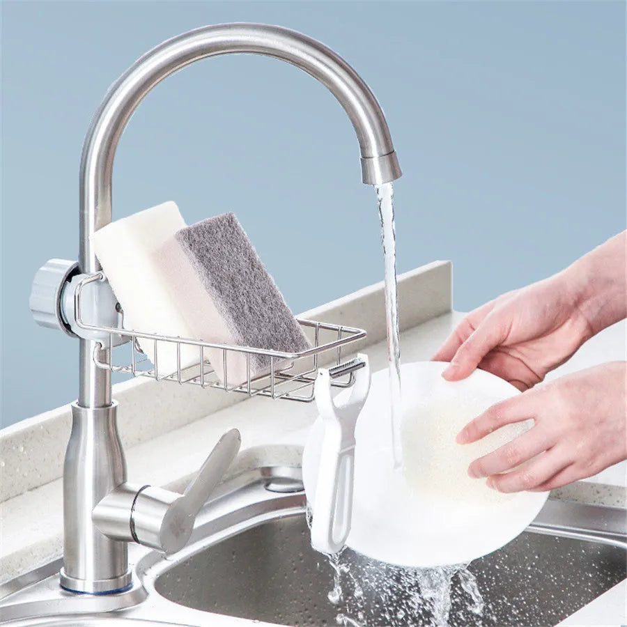 Adjustable stainless steel sink drain rack clipped onto a kitchen faucet with sponge and soap stored on the removable holder