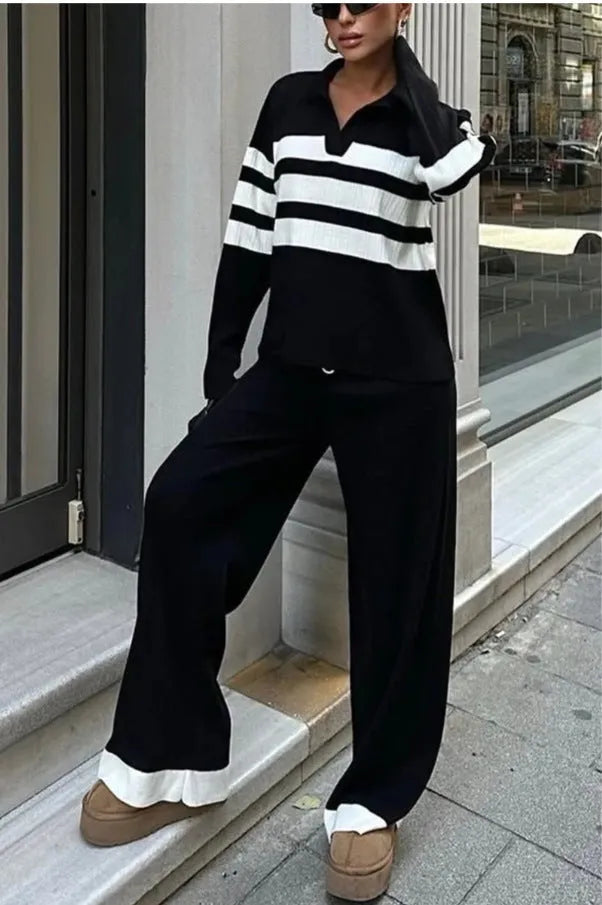Women's black and white striped knitted two-piece set with polo collar top and straight-leg trousers laid flat.