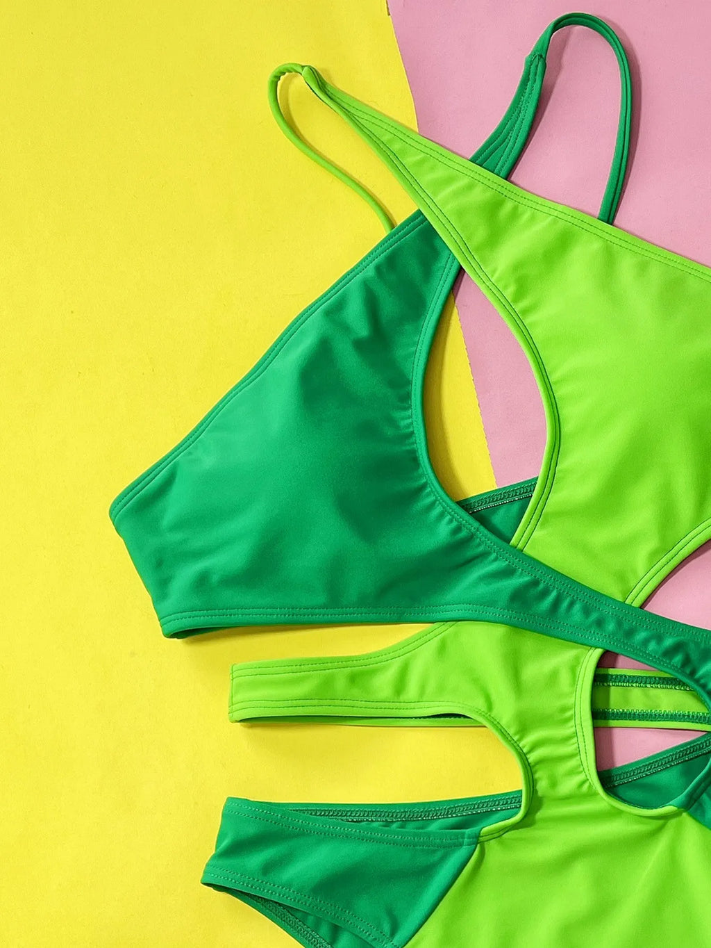 Green women's one-piece swimsuit with hollow contrast pattern on a mannequin.