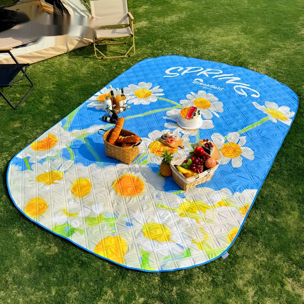 Waterproof thickened picnic mat in a seasonal colour, shown unrolled on grass.