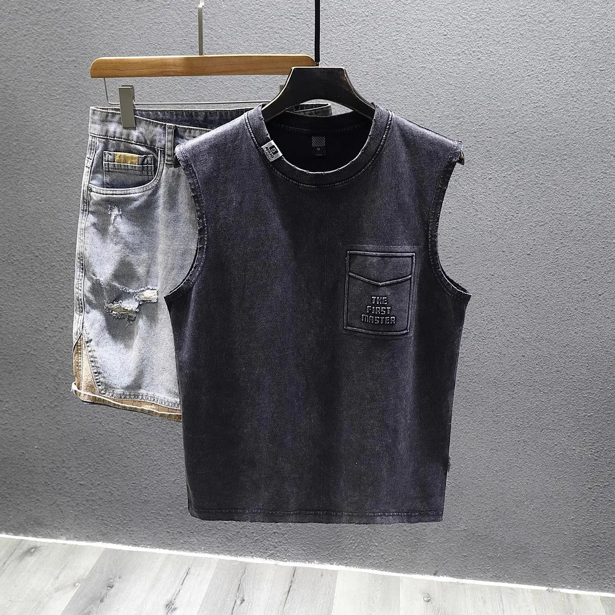 Men's loose fit black cotton sleeveless t-shirt on a hanger, showing straight hem design.