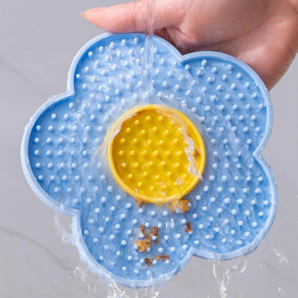 Flower-shaped silicone pet lick mat with suction cups on a smooth surface in assorted colours.