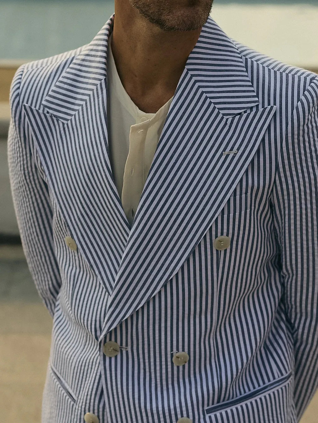 Blue and white striped men's polyester suit set with blazer and trousers on a model.