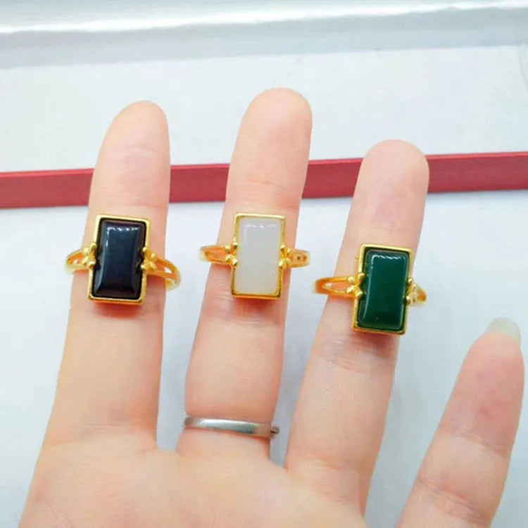 Close-up of an adjustable brass gold-plated ring with an electroplated finish and a green artificial gemstone inlay.