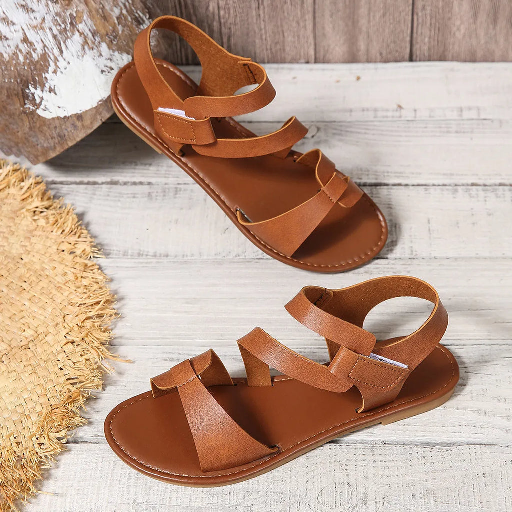 Women's flat sandals with a Velcro strap, in PU leather with a rubber sole.
