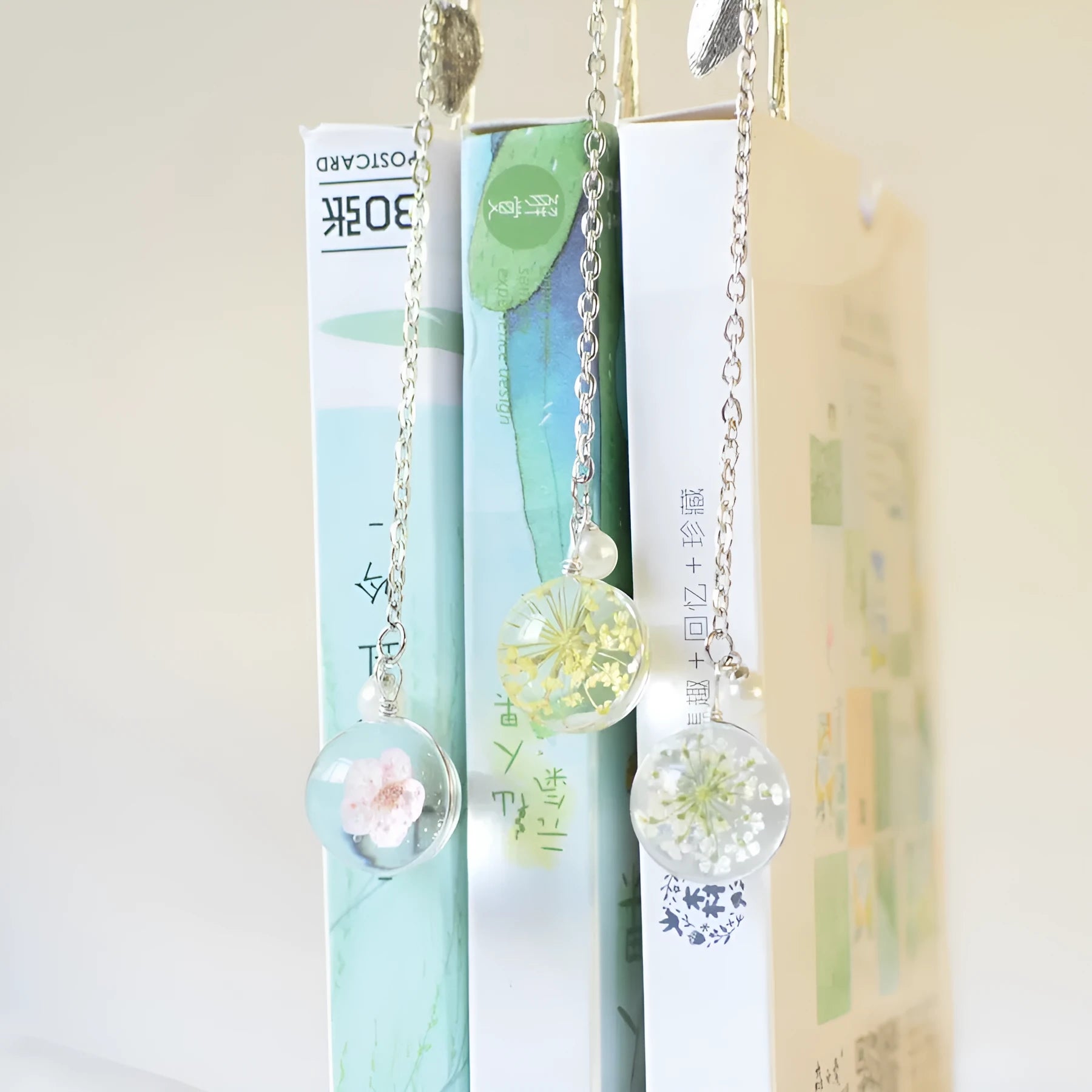 Close-up of a metal alloy bookmark with a preserved pink dried flower inside, measuring 12cm long, on an open book.