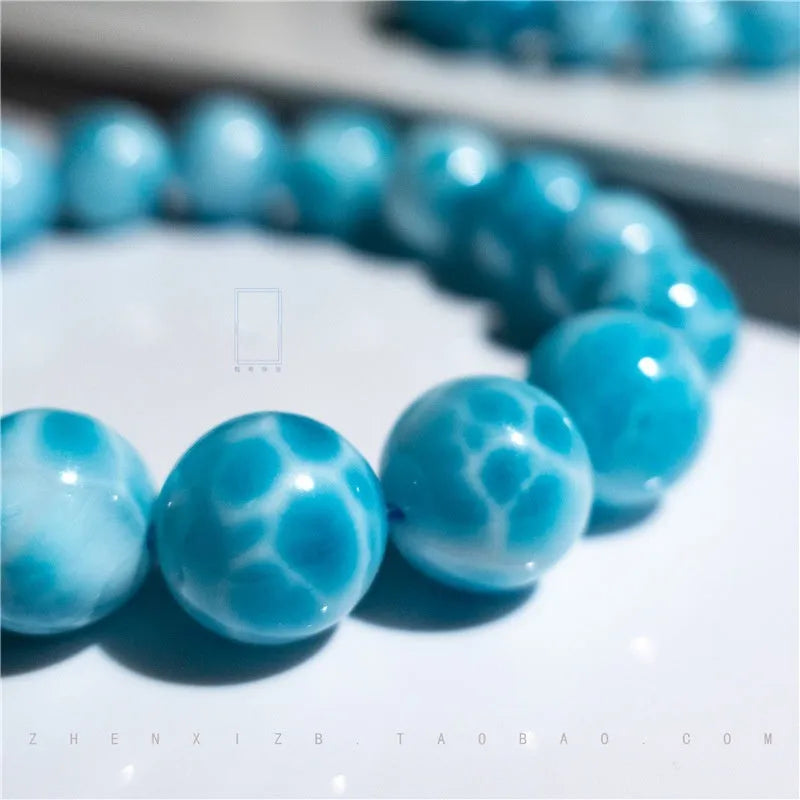 Blue natural crystal sea-pattern stone and Bodhi bracelet with pearl details on a white background.