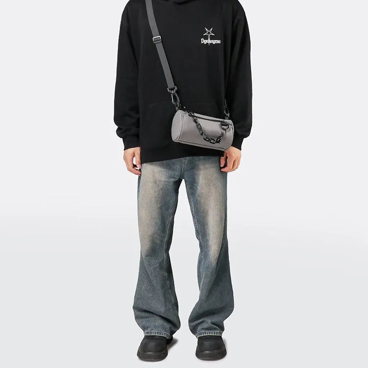 Black Oxford cloth messenger bag with a chain detail, worn crossbody.