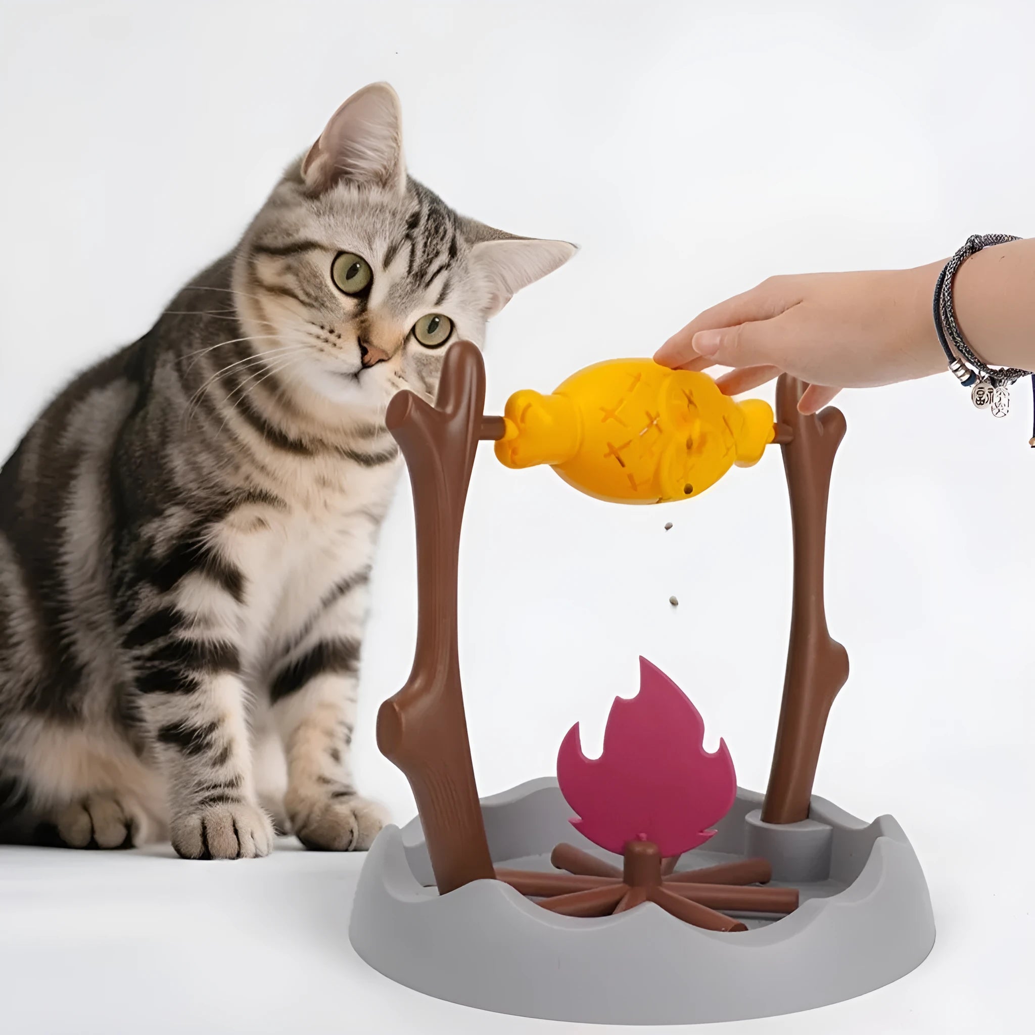 Barbecue-themed plastic tumbling cat treat feeder toy on a floor.