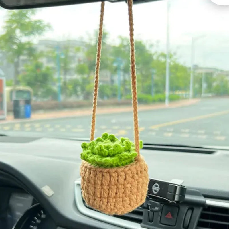 Green and white crocheted wool car plant decoration with a white hanging rope.