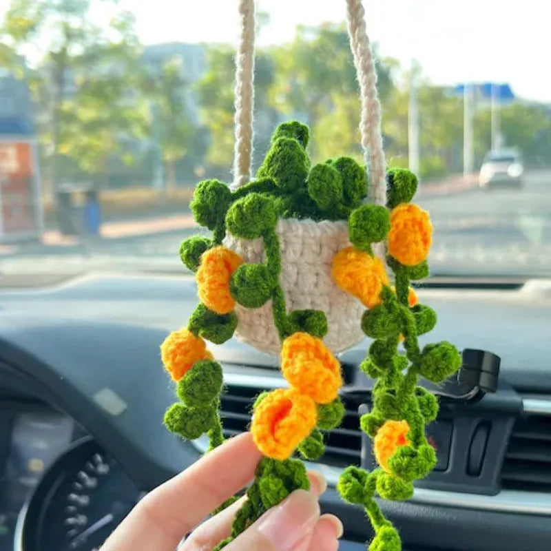 Green and white crocheted wool car plant decoration with a white hanging rope.