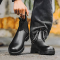 Vintage grey unisex Chelsea boots on a wooden floor, showing frosted PU upper, round toe, low heel, and car stitch detail.