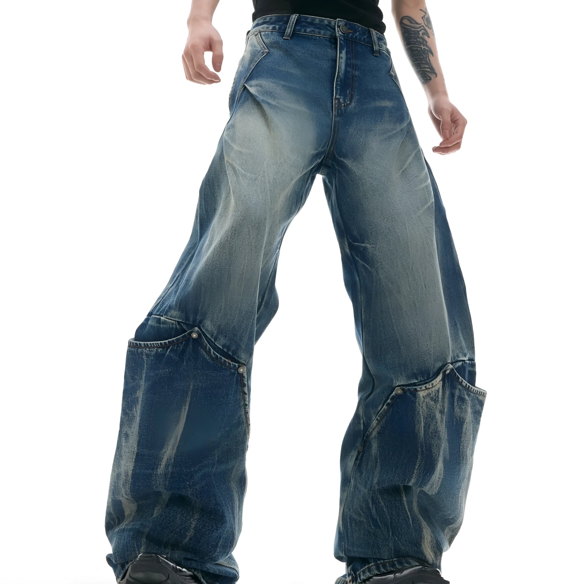 Man wearing verdant blue loose-fit jeans with curved seam detail and a vintage washed burst pattern.