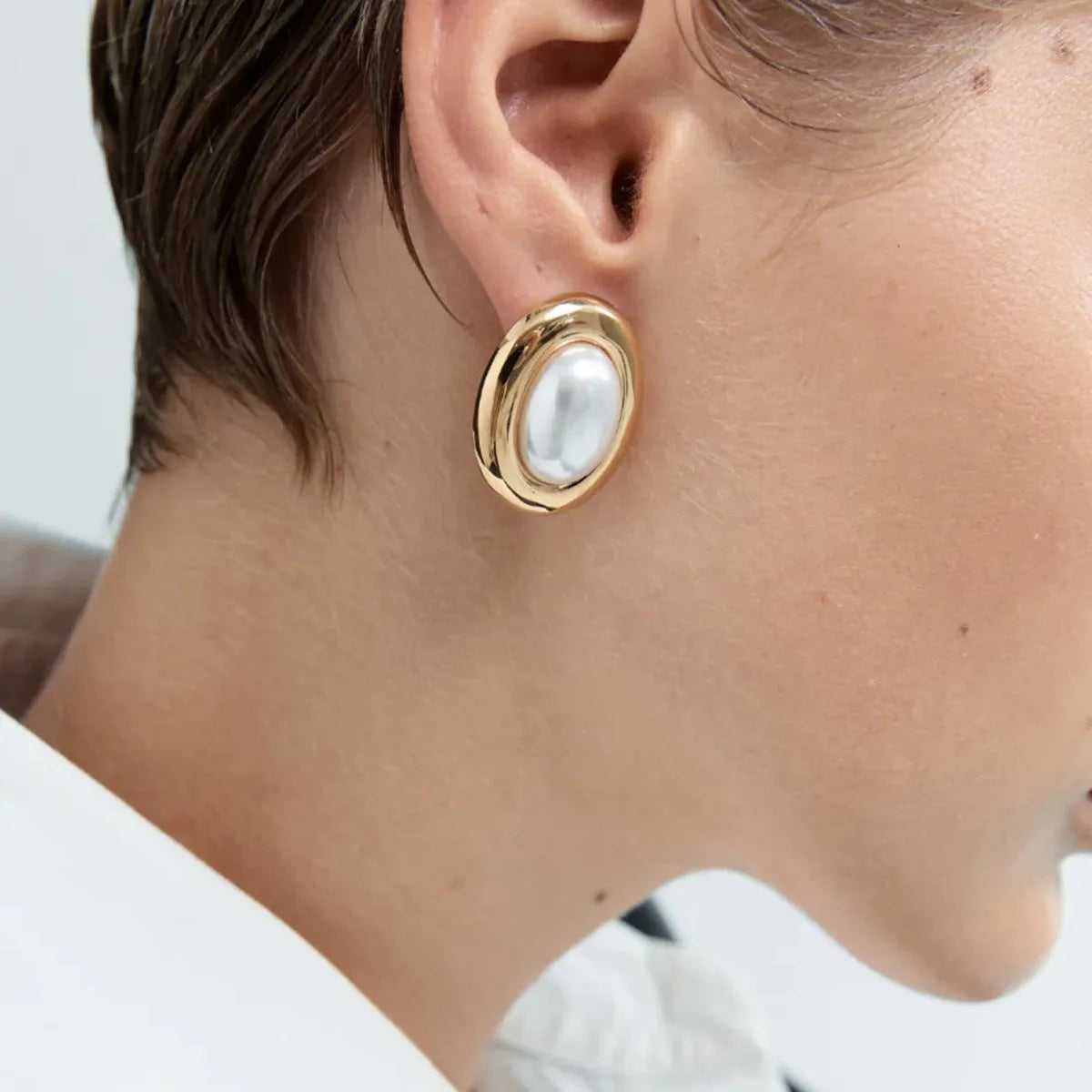 A pair of stainless steel vintage pearl stud earrings for women with a silver-toned finish and a fixed white pearl.