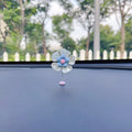 Small colourful plastic car decoration shaped like a swing, shown in blue, on a car dashboard.
