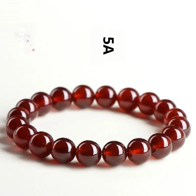 Natural orange red garnet ball bracelet with a silver Ruyi charm on a white background.