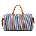 Large striped canvas travel duffel bag with contrast colour and leather detailing, horizontal square shape and zip top.